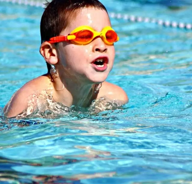 A child wearing goggles participating in a swim lesson