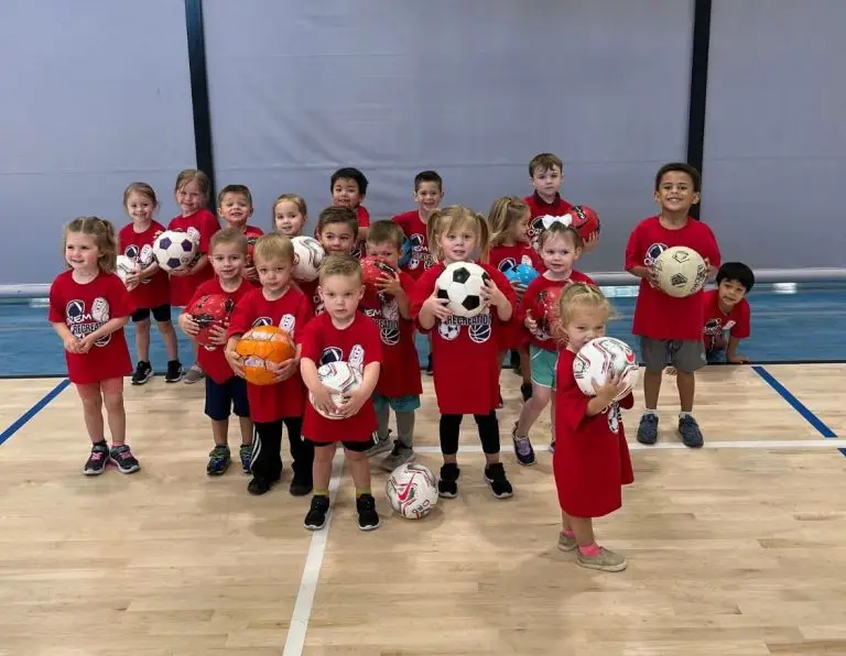 Little kids holding basketballs on a court.