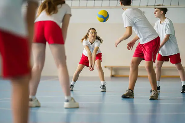 Group of teenage children play volleyball on the sports field