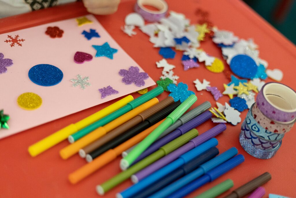 Arts and crafts table with colored pencils and paper laying on top of it.