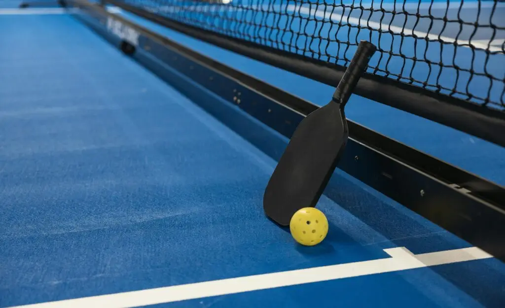 Pickleball and paddle on a pickleball court.