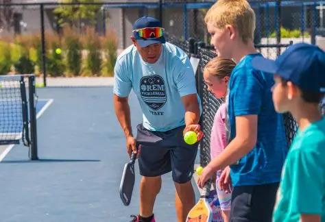 Youth being taught by an adult how to play pickleball