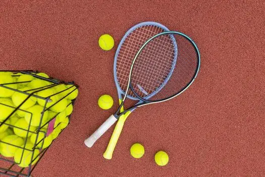 A photo of tennis equipment on the ground including 2 tennis rackets and tennis balls