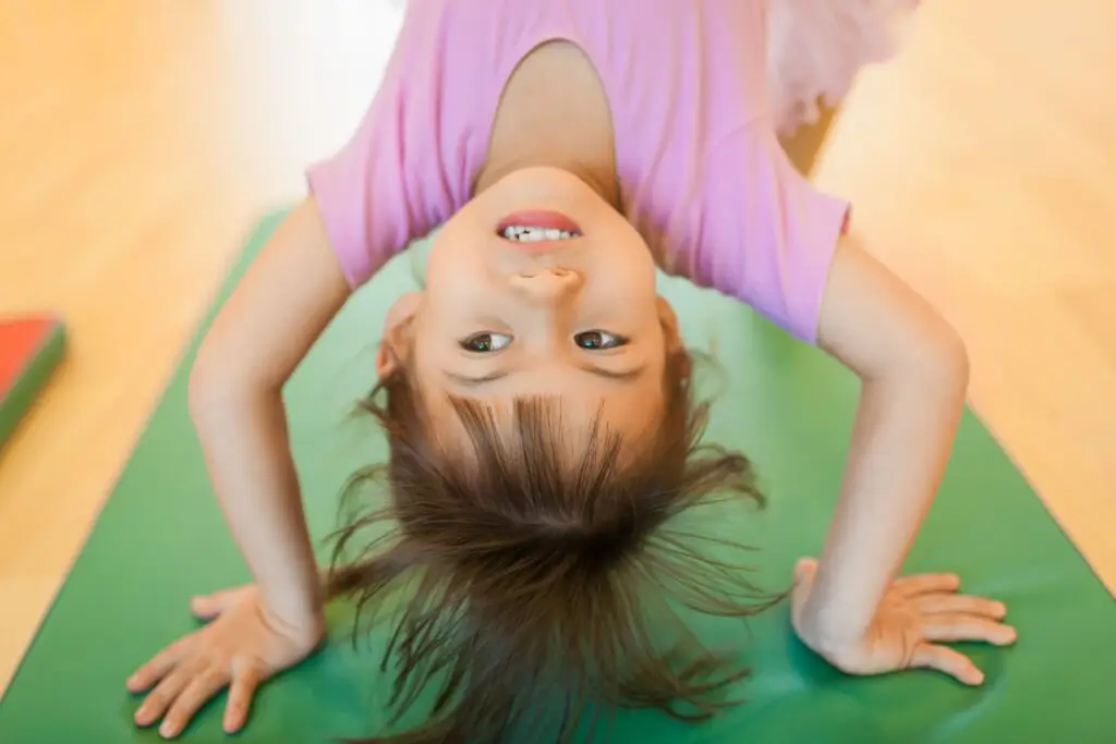 Little girl doing a back bend on a mat.